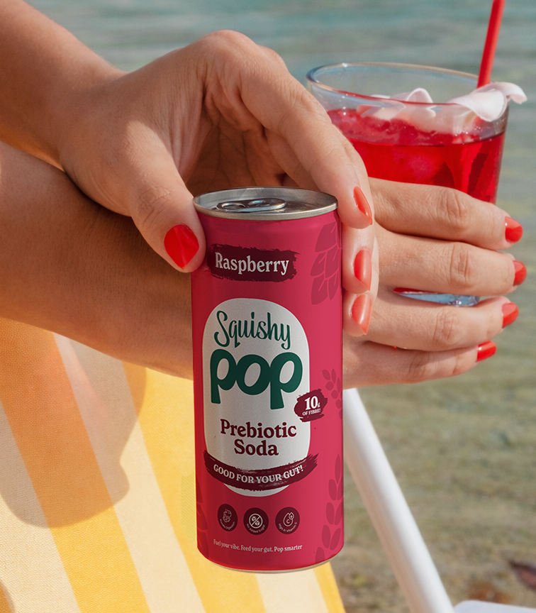 Someone holding a can of Squishy Pop on the beach